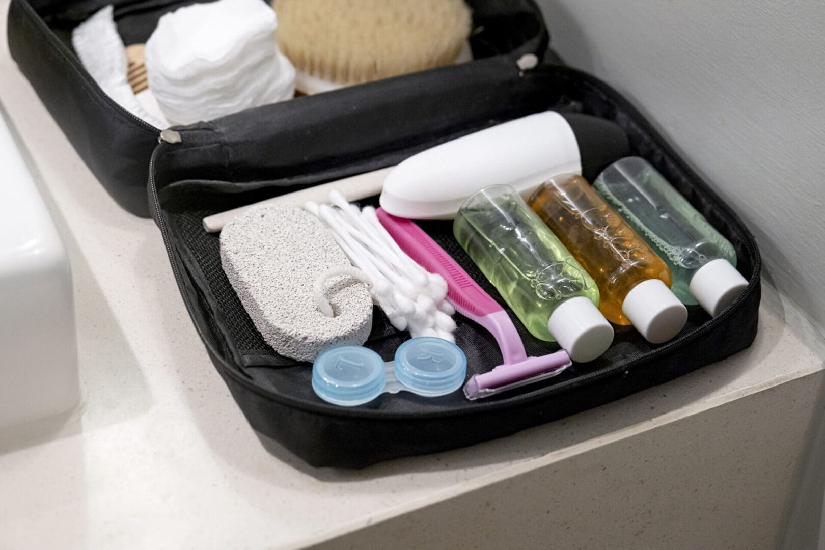 Travel cosmetics kit with bottles, brushes and cosmetics on shelf in hotel bathroom , packing for vacation